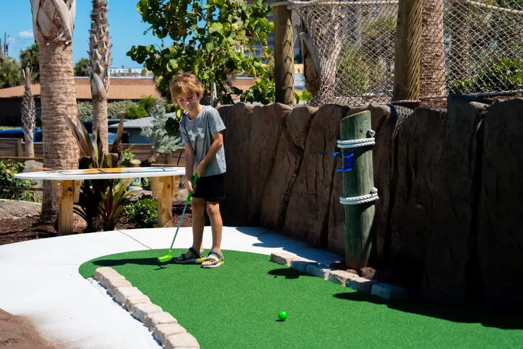 kid playing mini golf
